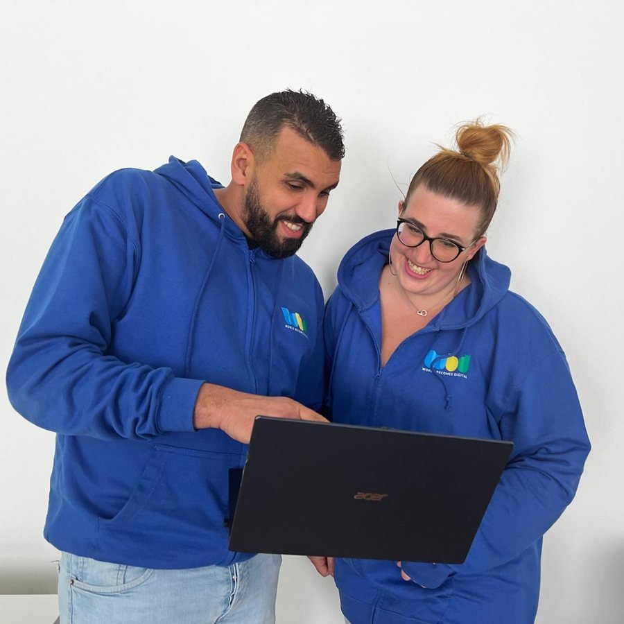Deux membres de l'équipe WBD consultent un ordinateur portable en souriant
